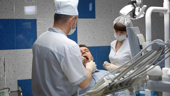 Male Client Having Her Teeth Examined by Dentist