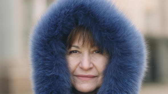 close-up Beautiful caucasian woman in a blue fur hood smiling and looking at the camera. Portrait of alt