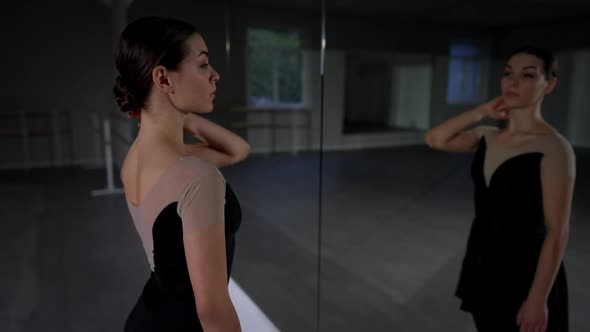 Medium Shot Slim Woman Turning Looking at Camera Reflecting in Ballet Studio Mirror alt