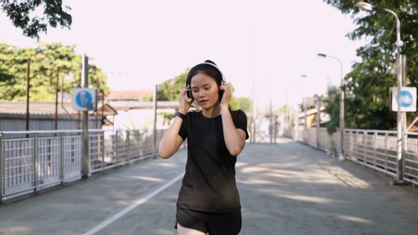 Happy girl athlete running wearing headphones using a smartphone listening to music running. alt