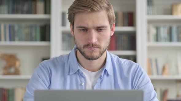 Portrait of Man Thinking While Working on Laptop alt