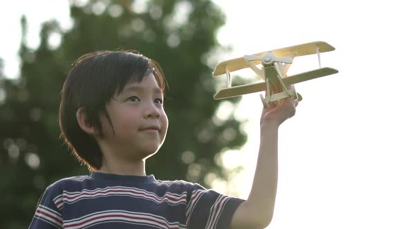 Cute Asian Child Playing Wooden Airplane In The Park Outdoors Slow Motion  alt