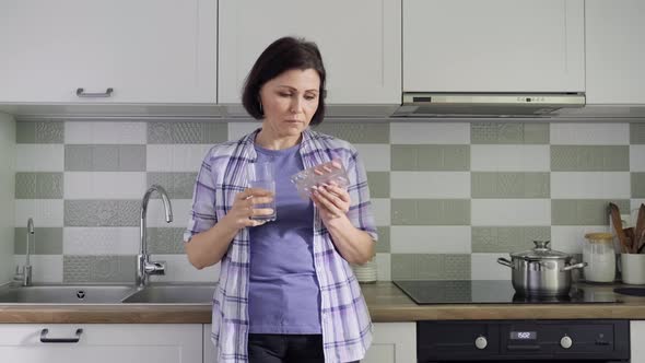 Middleaged Woman Drinking Vitamins Tablets Drinking a Glass of Water alt