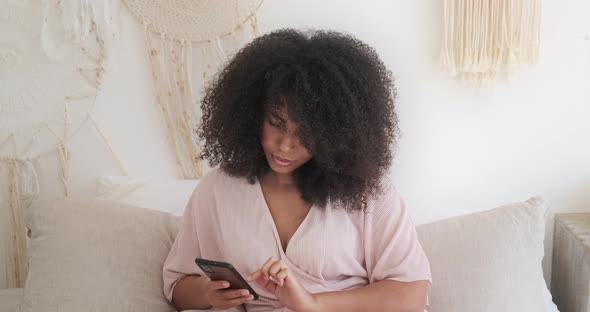 Thoughtful Young Mixed Raced Woman Using Smartphone Enjoying Chatting with Boyfriend
