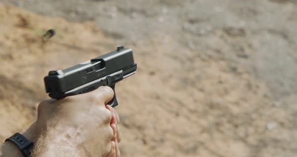 Close up footage of a hand gun firing in a firing range with cartridge flying away