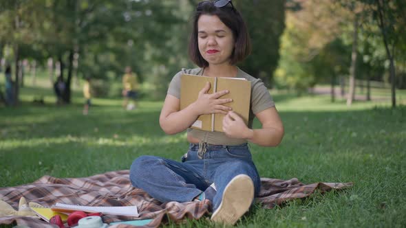 Happy Young Woman with Dwarfism Hugging Book Reading Romantic Poem in Summer Park alt