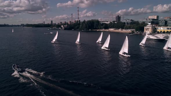 Bird's Eye View of Yachts Racing Fast on the River on the Background of the Marina with Moored Boats