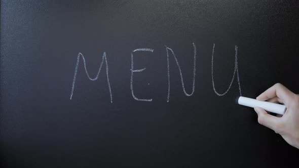 Hand writes word Menu on chalkboard. Menu written on black sign board alt