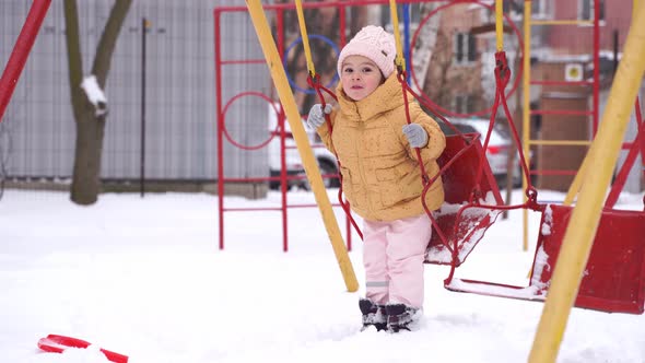 Toddler Girl Playing on Playground in Winter alt