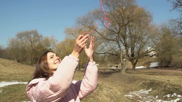 A Girl in a Pink Jacket Throws Up a Ball of Threads in an Autumn Spring Park Slow Motion alt