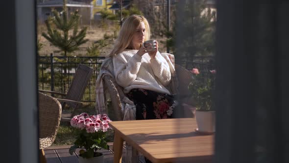 beautiful caucasian woman drinking tea on the terrace with flowers