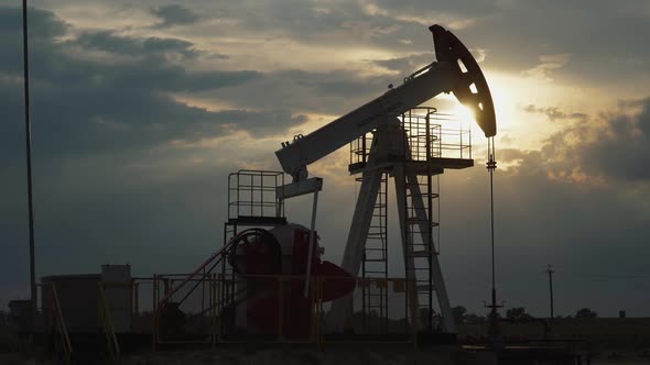 Oil Mining, an Oil Rig in the Field Pumps Out Oil, View of an Oil Rig at Sunset, Resource Extraction alt