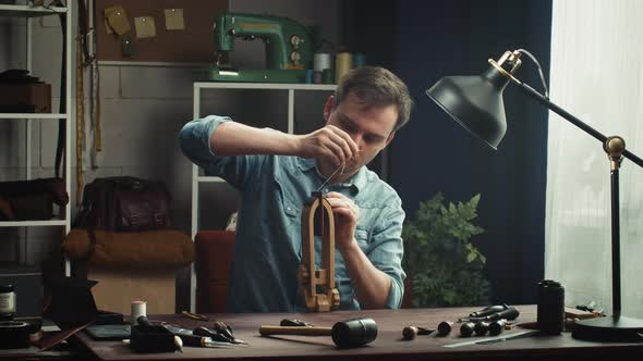 Man Tailor Sewing Two Pieces of Leather on Stand Using Professional Sharp Needle and Strong Thread alt