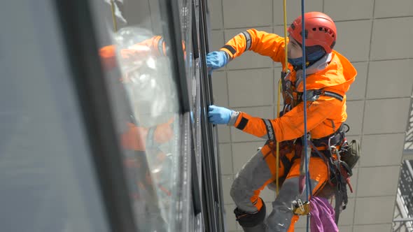 Professional Equipped Climber Washes Windows with Rubber Screed High Altitude, Slow Motion alt