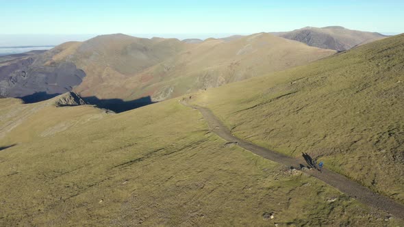 Aerial view of people hiking and climbing Snowdon mount in Wales on a sunny d alt