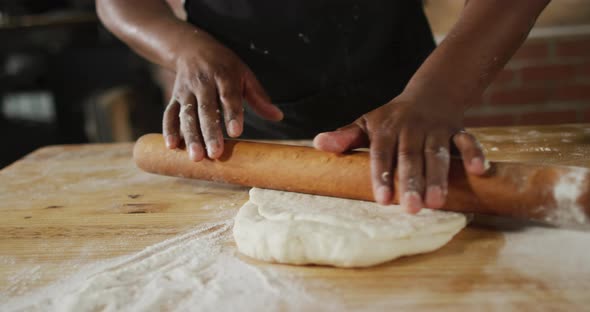 Animation of hands of african american male baker rolling sourdough for bread alt