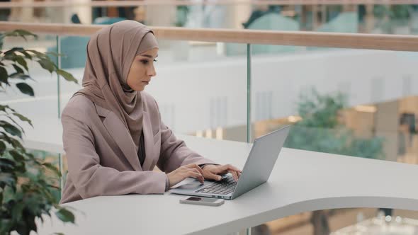 Focused Serious Arab Businesswoman Professional Entrepreneur Sitting at Office Desk Typing Looking alt
