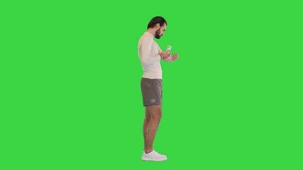 Fitness Man with Mobile Phone Connected to a Smart Watch on a Green Screen Chroma Key