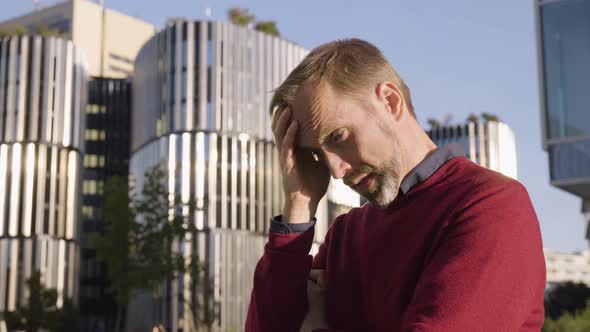 A Middleaged Handsome Caucasian Man Thinks About Something and Acts Sad in an Urban Area alt