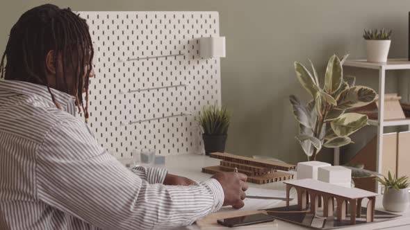 African American Engineer Drawing Paper Plan in Office alt