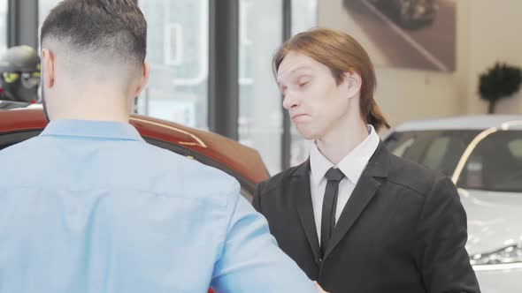 Young Salesman Talking to a Customer at Car Dealership