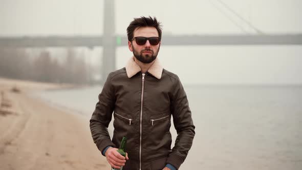 Relaxed Handsome Man Drinking Beer. Man Celebrating And Drinking Cold Beer Outdoors From Bottle. alt