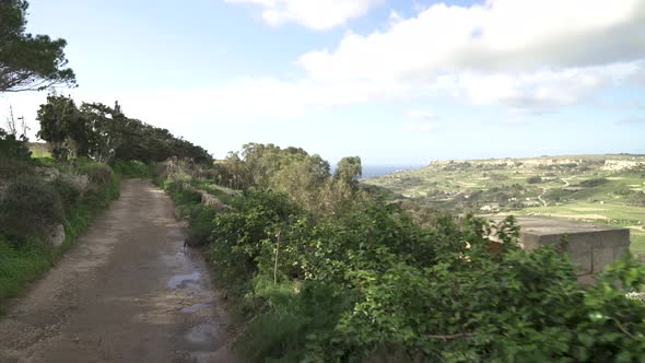 Walking on a High Hill Road in Malta near Farmlands in Canyon