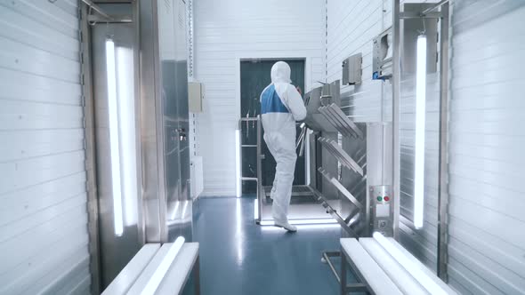 a Production Worker in a Special Uniform Disinfects His Hands