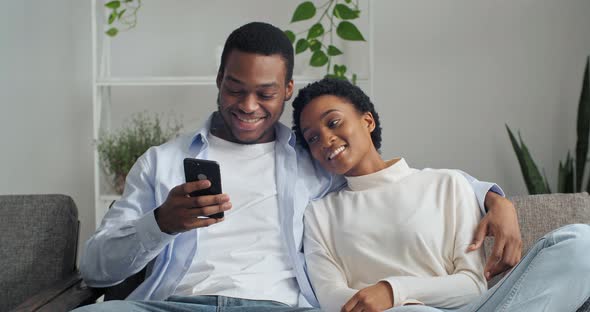 Happy Young Husband Showing Funny Video in Social Network on Cellphone Beautiful Wife alt