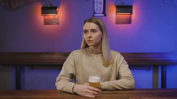 Portrait of a Happy Woman in Pub with Glass of Beer in Hand at Bar Counter