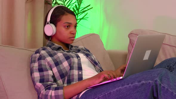 Tired Woman Lying on the Couch with a Laptop Listening to Music