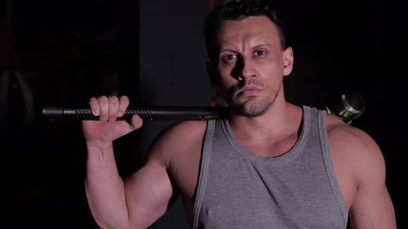 Man with Big Muscles Holds a Heavy Hammer Slung Over His Broad Shoulders