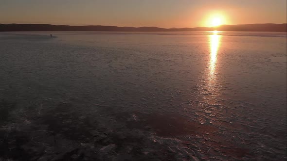 Northern Landscape Frozen Lake Drone Flying Down with Beautiful Reflection on Ice at Sunset