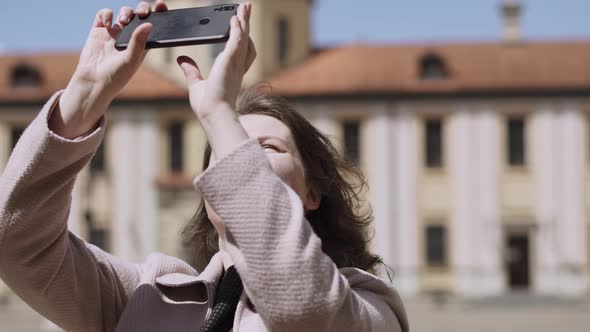 Delighted Woman Takes Pictures Shoots Video on Phone in Courtyard of Castle alt