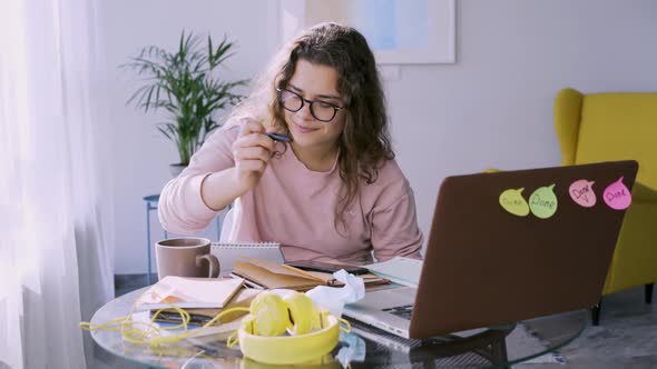 Woman Freelancer Writes Looking in Laptop at Small Table