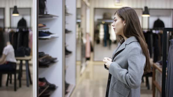 A Side View Close Up Video of a Female Customer of a Clothing Boutique Trying on a Grey Overcoat and