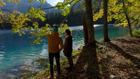Couple standing at lakeside, Parco Naturale dei Laghi di Fusine, Italy alt