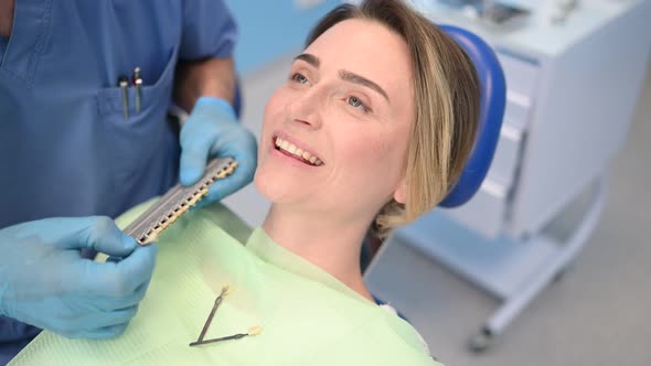 Dentist Checks the Level of Patient's Teeth Whitening with a Dentist's Color. Dental Equipment in