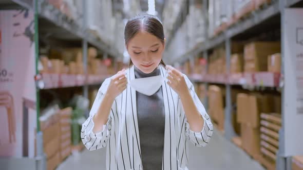 Portrait of asian woman business owner taking off face mask at distribution warehouse