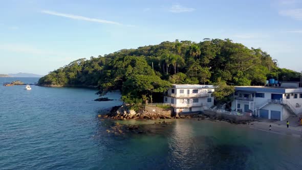Aerial shot of a building beside a hill covered by vegetation in Praia da Sepultura beach. Dolly in alt