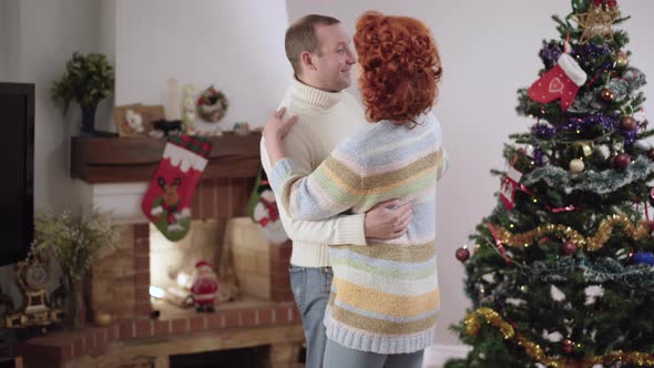 Middle Shot of Happy Caucasian Man and Woman Dancing on New Year at Home Talking and Smiling alt