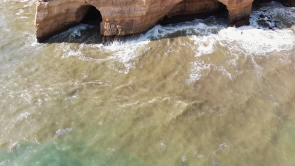 Caves in Benagil coast in Algarve, Portugal - Tilt up Reveal Aerial shot alt