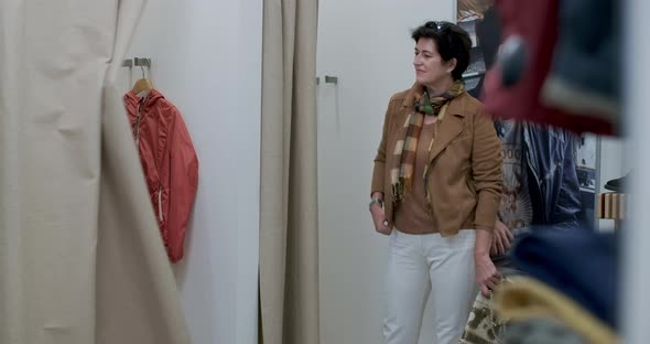 Confident Woman Standing in Shop Dressing Room As Young Female Shopper Opening Curtain and Going Out alt