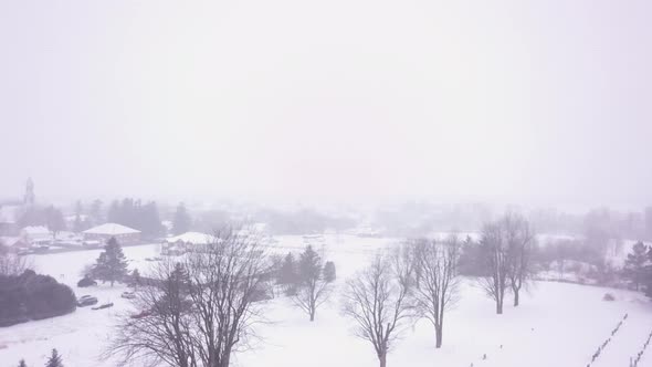 Slow aerial panning shot of a small town during a snowstorm alt
