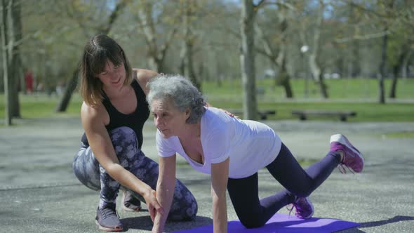 Smiling Senior Woman with Young Trainer During Workout in Park. alt