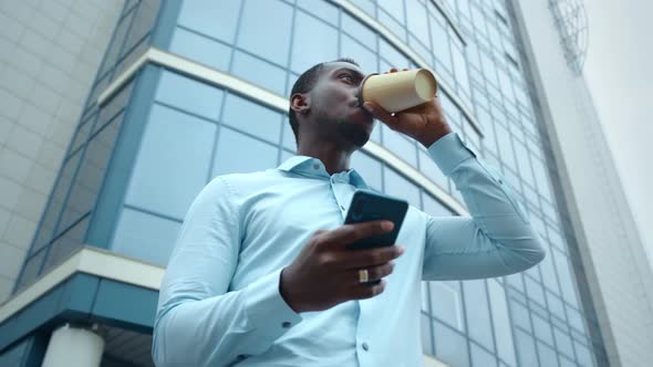 Portrait of Stylish Black African Man Walking Down the Street Using Smartphone for Social Media. alt