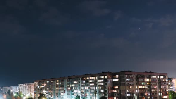 Stars and Night Clouds Move Over Multi-story Buildings. Night City. Timelapse alt