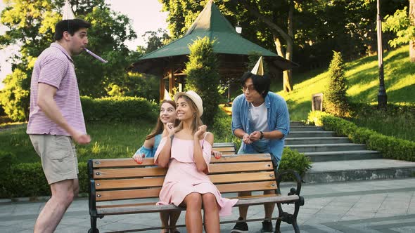 Birthday Girl Using Mobile Phone Sitting on Bench in Park alt