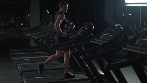 Ypung Athletic Man Run on a Treadmill Aerobic Exercise and Endurance Training in the Gym Night alt