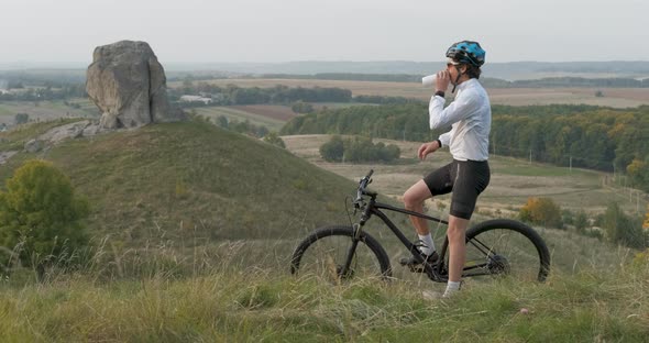 Professional Cyclist Makes Stop to Drink Water on the Hill with Beautiful View